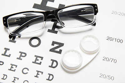 Glasses and contact lenses on top of an eye chart